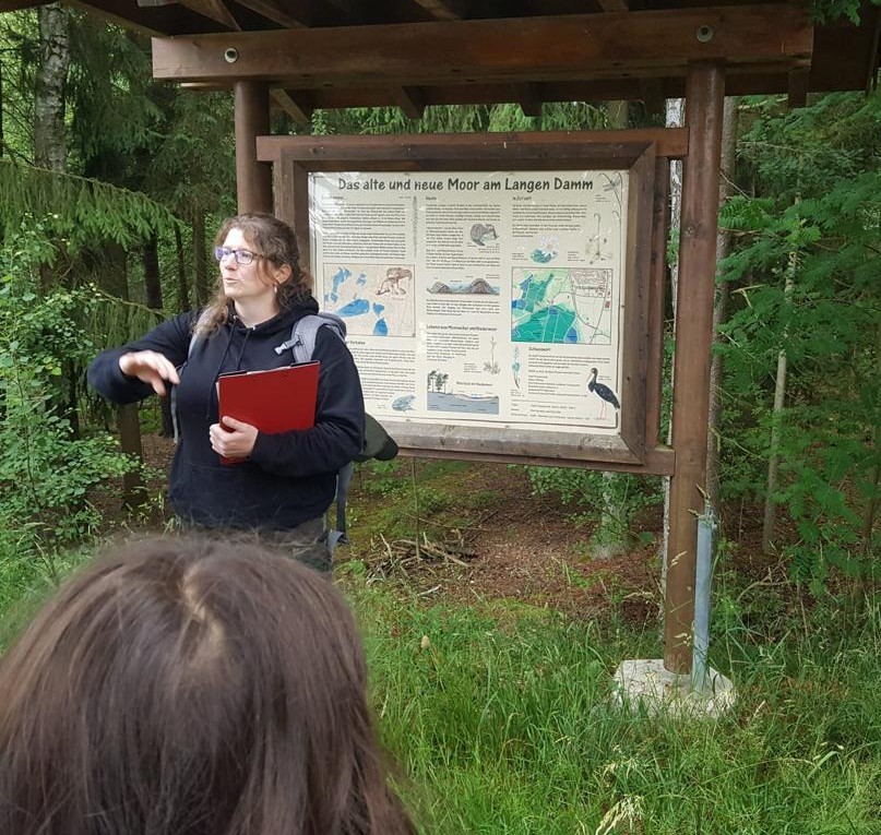 Frau vor einem Hinweisschild am Waldrand