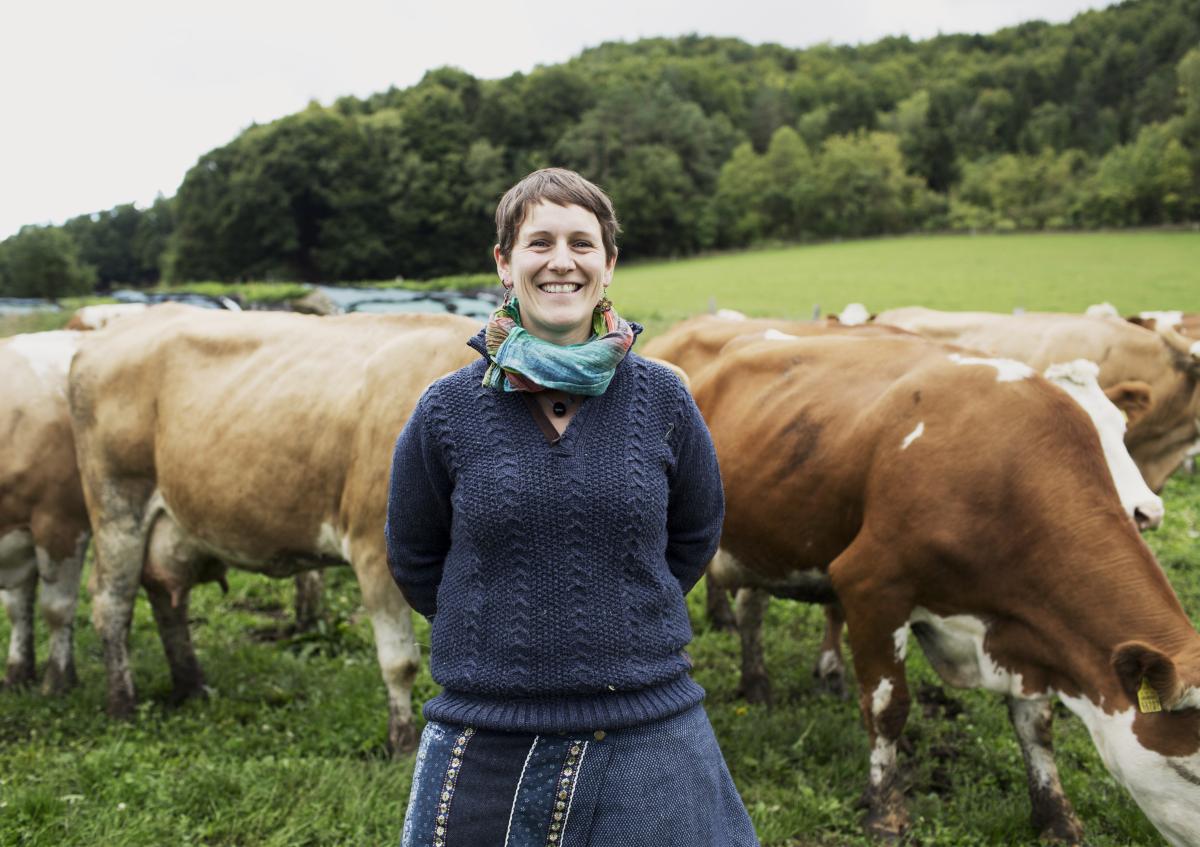 Eine Frau steht vor ihrer Kuhherde auf der Weide.