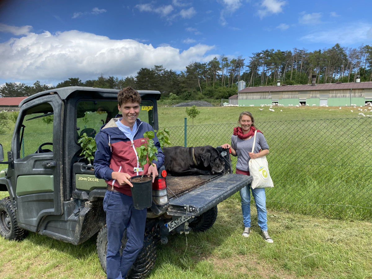 Landwirt Tim Ritter mit Haselnusspflanze vor Wagen, daneben Projektmanagerin Dr. Maike Hamacher