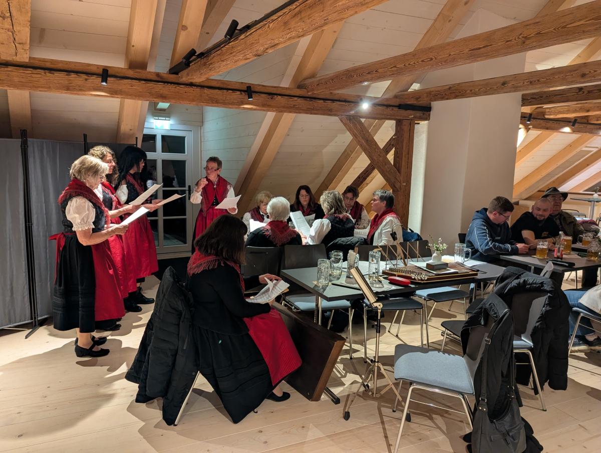 Menschen in Tracht stehen in einem Raum und musizieren