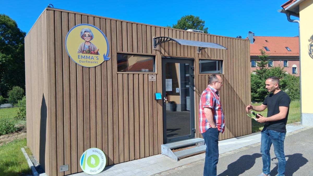 Einkaufsmöglichkeit in einem Container, davor stehen 2 Menschen