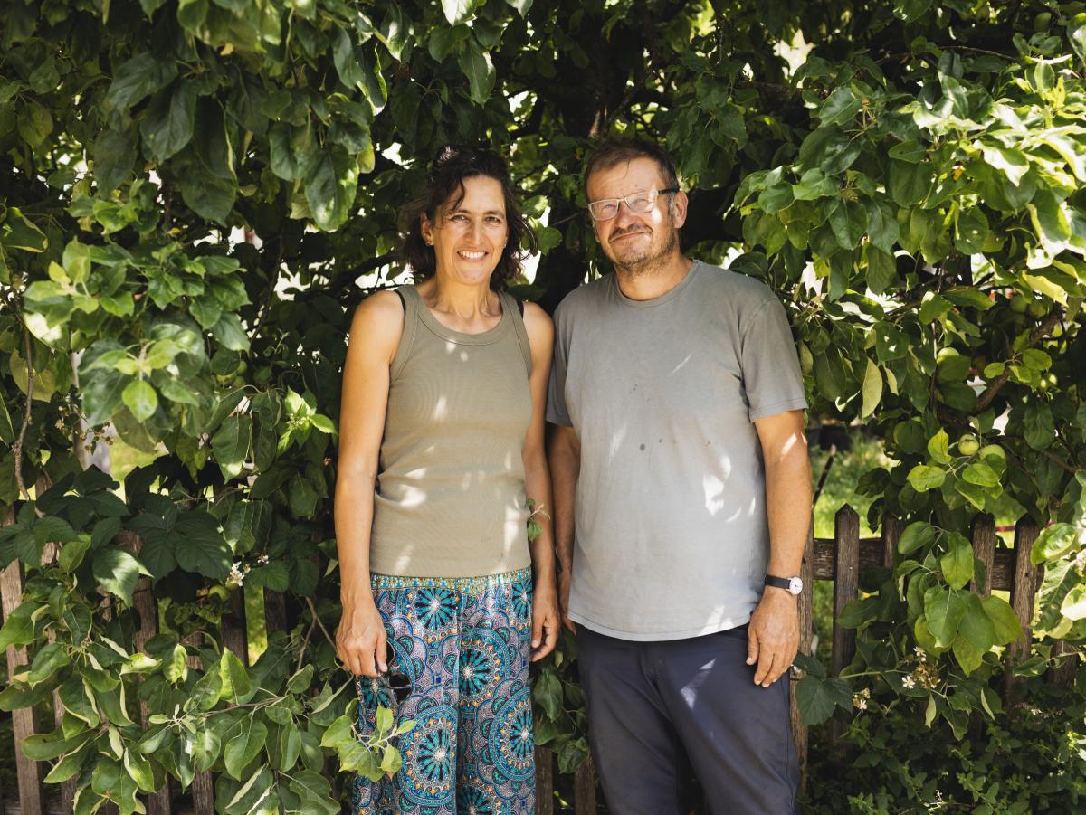 Eine Frau und ein Mann stehen vor einer Hecke.