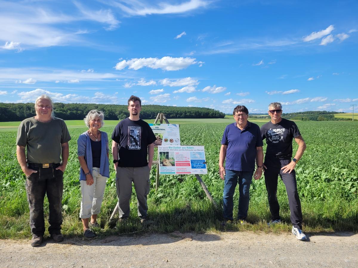 Gruppenfoto mit 5 Personen vor einem Zuckerrübenfeld