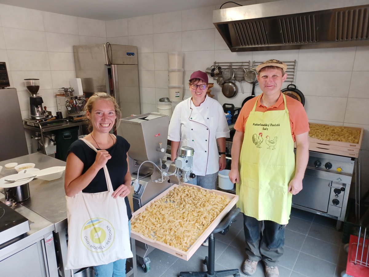 3 Menschen in Küche stehen um Nudelmaschine