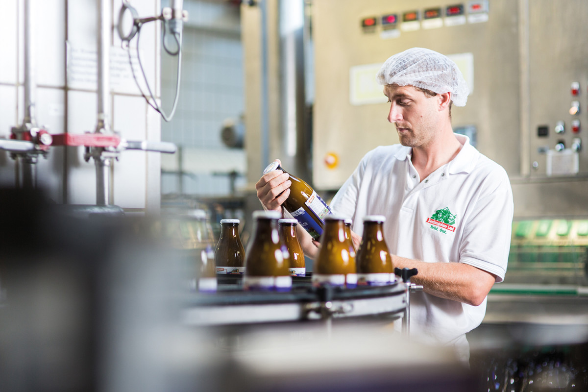 Die in der 1 Liter braunen Mehrwegflasche verpackte Biomilch kommt beim Kunden besonders gut an. Im Bild: Paul Althammer, stellv. Produktionsleiter bei der Flaschen-kontrolle