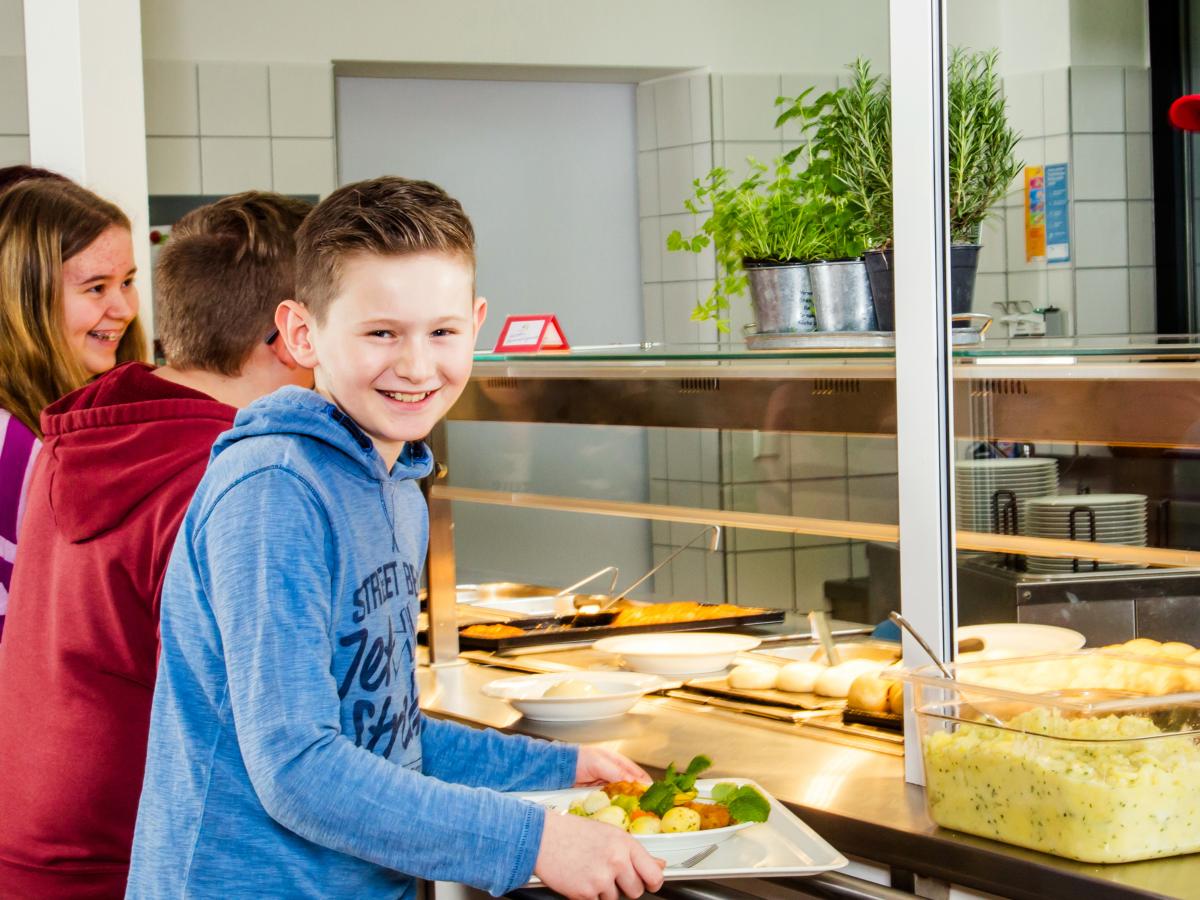 Kinder stehen an der Essensausgabe der Mensa