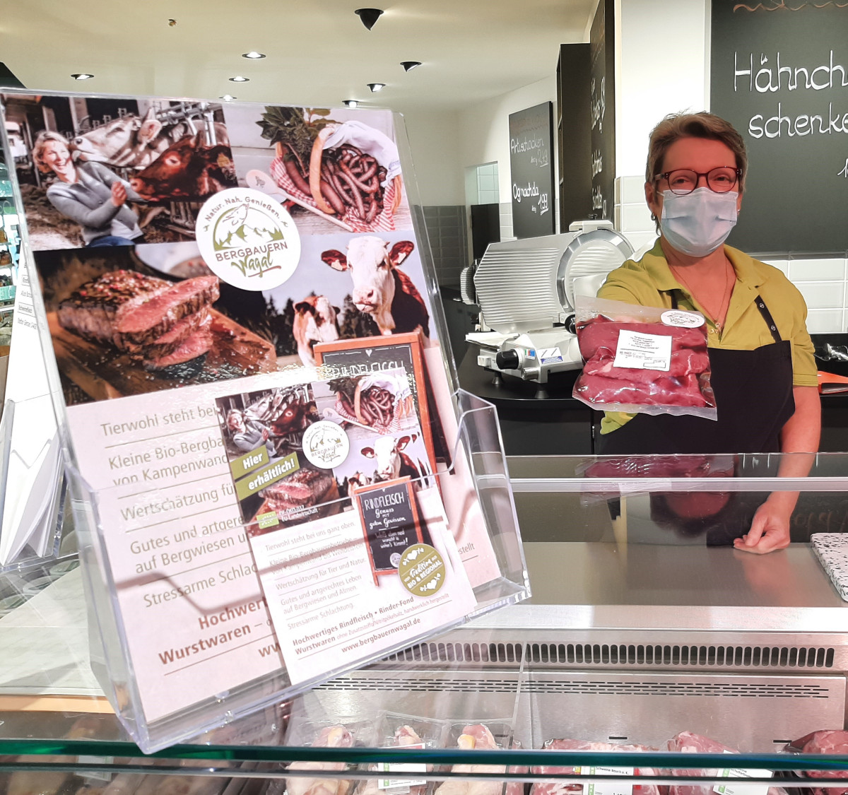 Eine Fleischwarenfachverkäuferin reicht Bio-Rindfleisch über die Theke