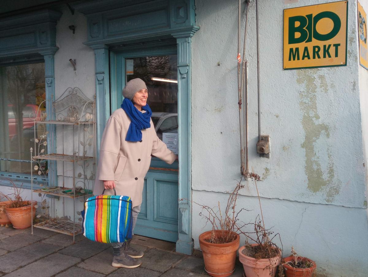 Eine Kundin verlässt lächelnd den Bioladen