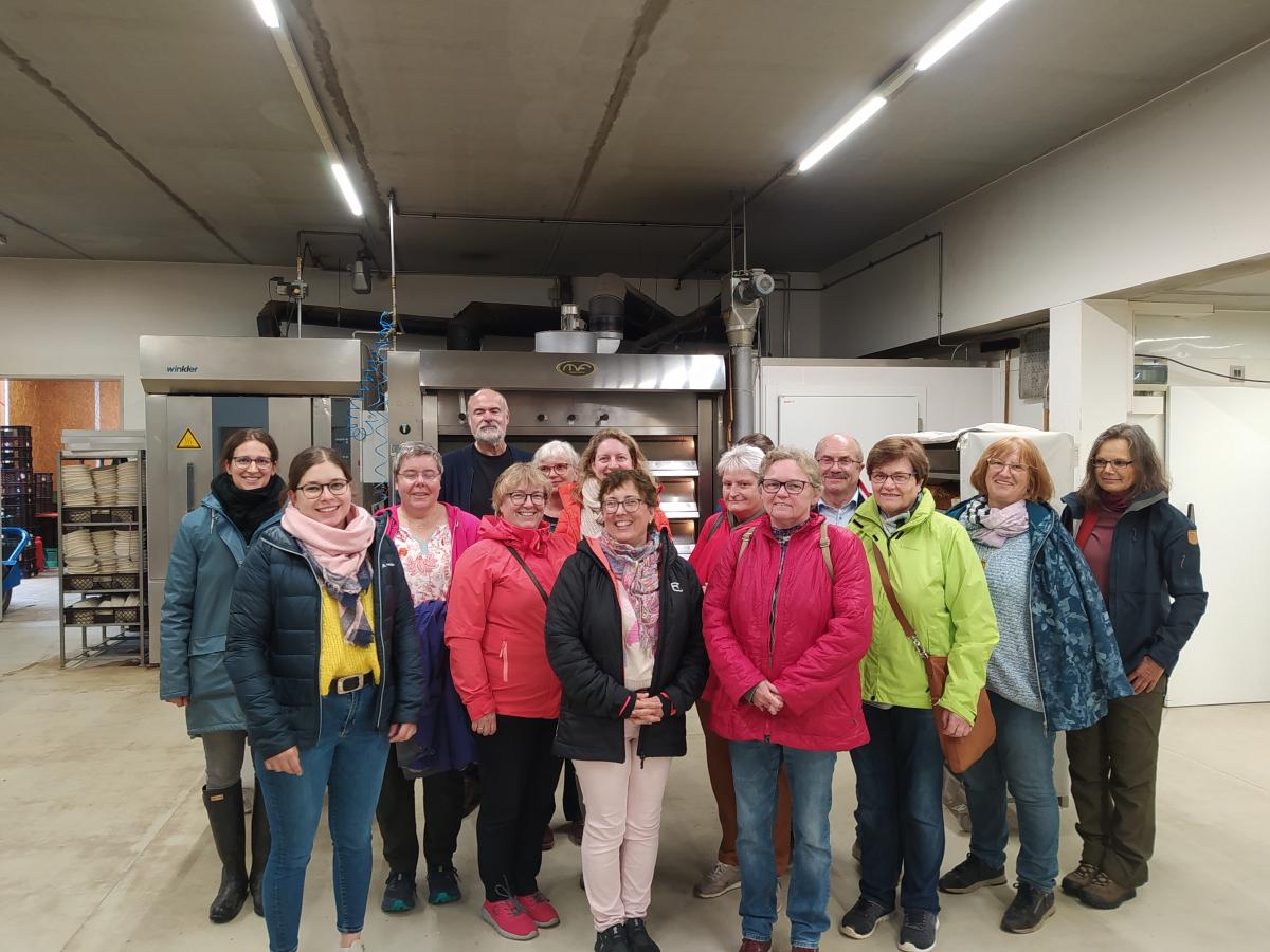 Mehrere Personen stehen im Halbkreis in einer Bäckerei und lachen in die Kamera.