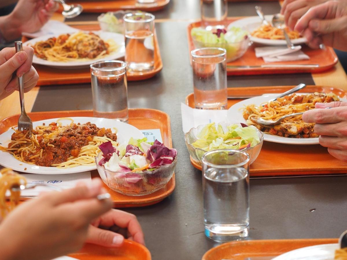 Tabletts asu Tisch mit Spaghetti und Salat.