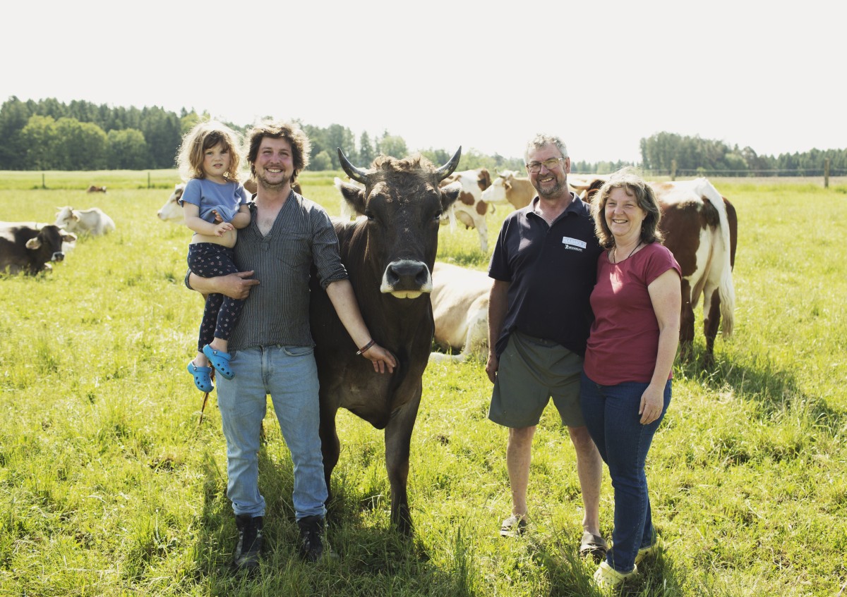 Familie Hauer steht mit einer origial Braunviehkuh auf der Weide.