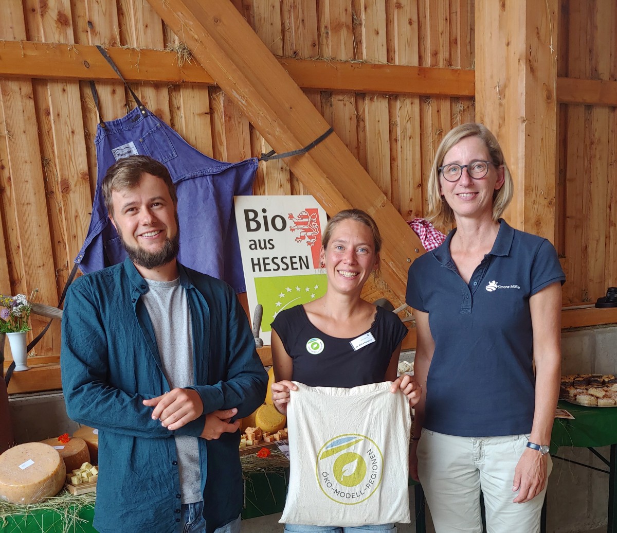 drei Menschen vor Stand mit Bio-Käse