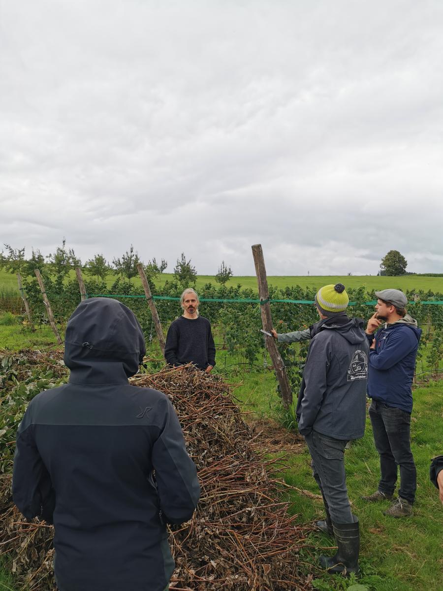 Das Foto zeigt einen Mann auf einem Feld, der einer Gruppe etwas erklärt.