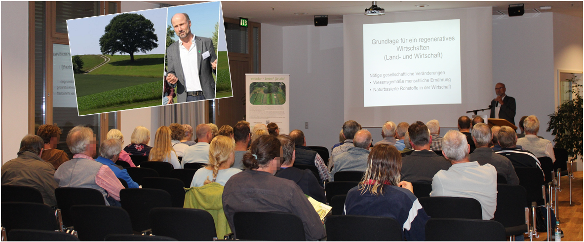 Gäste sitzen im Saal, vorne steht der Referent mit seiner Präsentation.