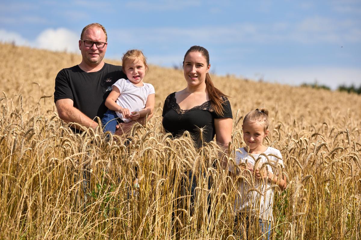 Familie mit 2 Kindern steht im Getreidefeld