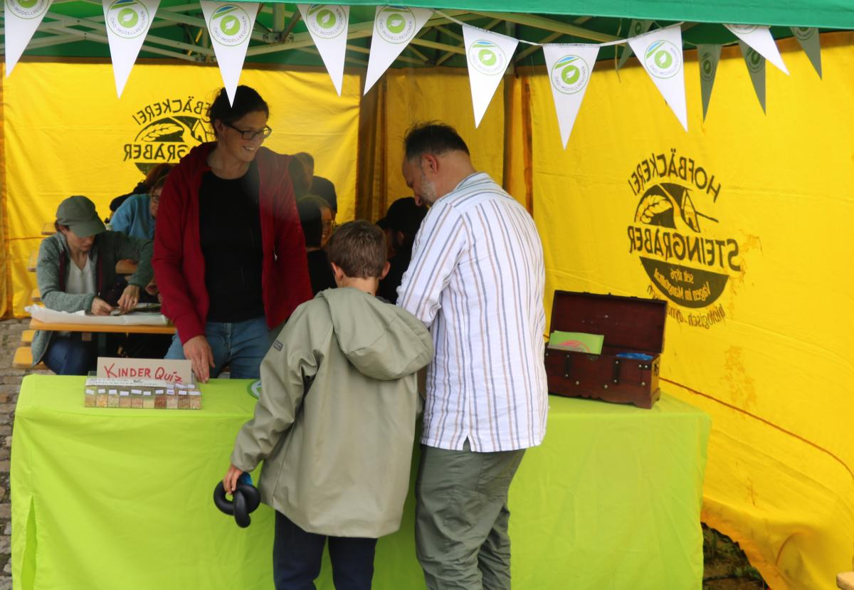 Ein Vater steht mit seinem Sohn am Infostand