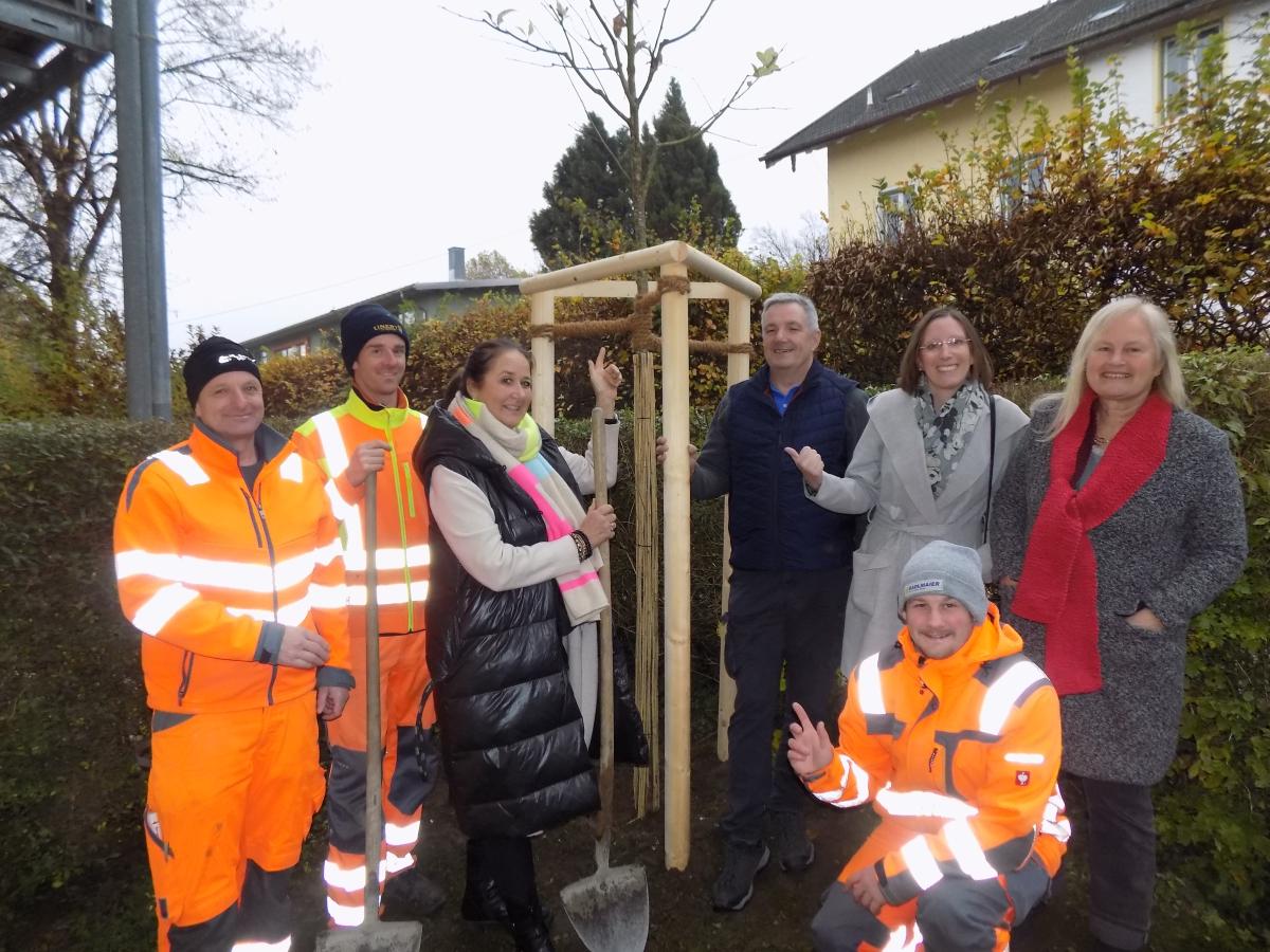 Nach der Pflanzaktion: Bauhofleiter Konrad Posch, Landschaftspfleger Sebastian Geier, Baumspenderin Marion Liertz, die Gemeindeoberhäupter und Sprecher der Ökomodellregion Waginger See-Rupertiwinkel, Matthias Baderhuber und Stefanie Lang, die Projektmanagerin der ÖMR, Marlene Berger-Stöckl, sowie Simon Wegscheider vom Bauhof zeigen nach getaner Arbeit stolz auf die frisch gepflanzte Mehlbeere.