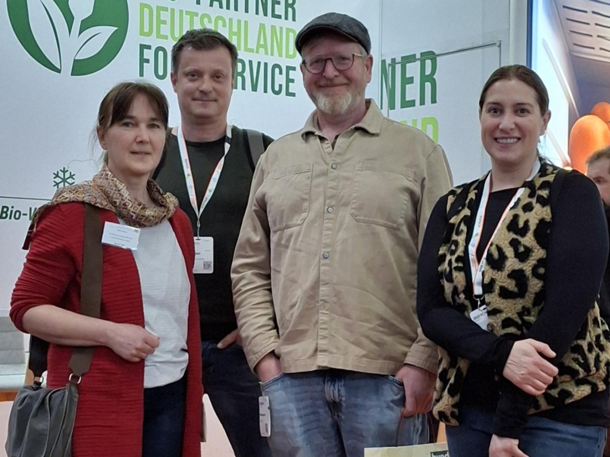 Vier Personen stehen da und schauen in die Kamera