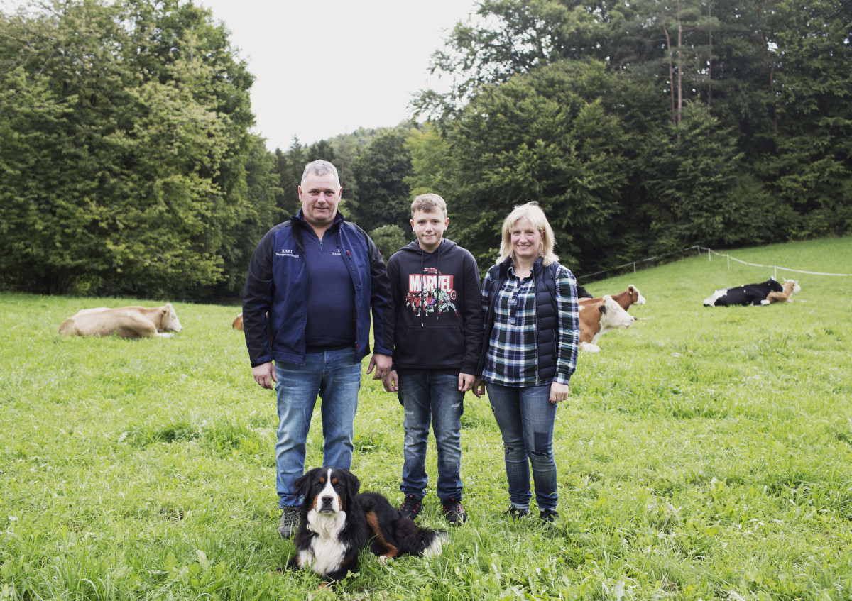 Mehrere Personen und ein Hund stehen auf einer Rinderweide. Im Hintergrund liegen die Rinder.