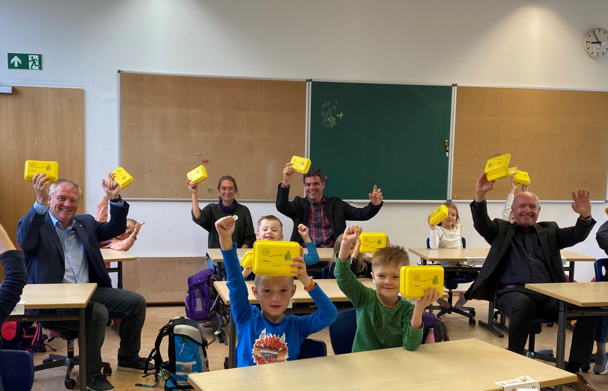 Schüler mit gelben Brotboxen in der Hand