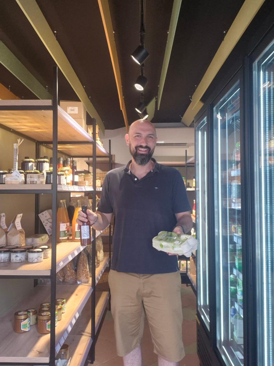 Mann steht in kleinem Laden mit Produkten in der Hand