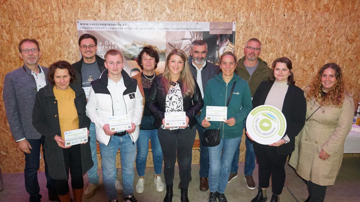 Eine Gruppe von Menschen die eine Förderplakete für die Kleinprojekt Förderung der Öko-Modellregion in der Hand halten