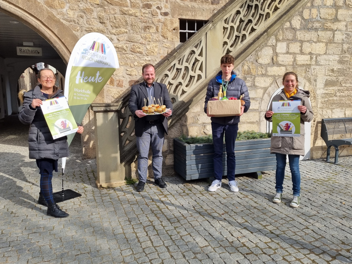 4 Personen vor Rathaus Ostheim mit Werbematerial für den Regionalmarkt OStheim